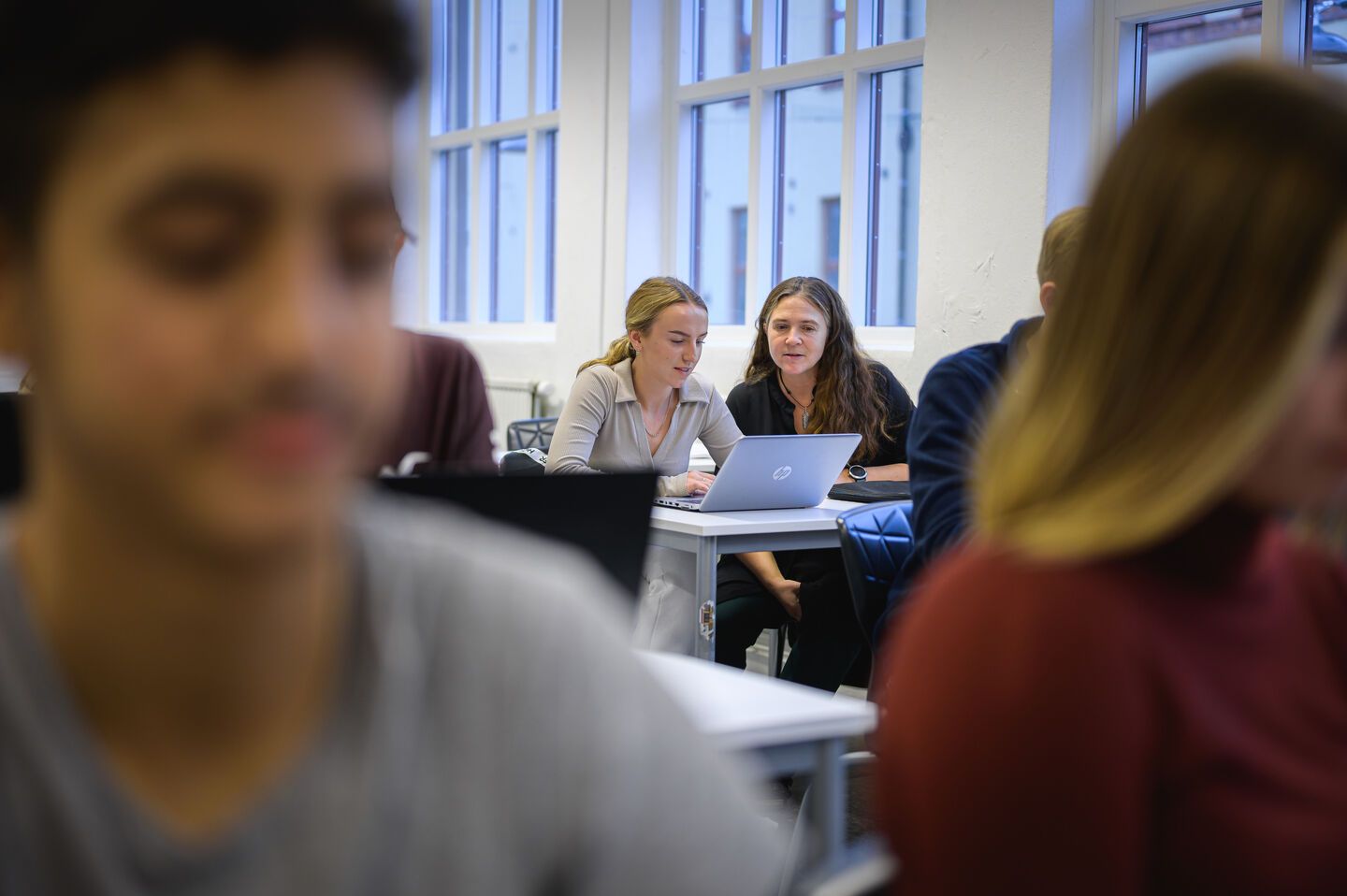 Elever i ett klassrum som tittar på en laptop tillsammans.
