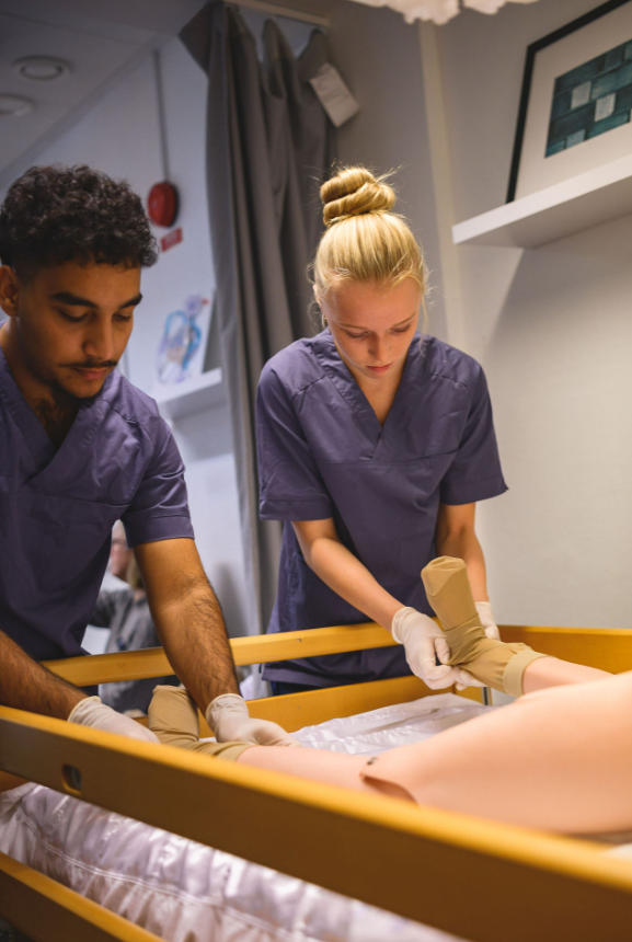 elever sätter på strumpor på docka inom vård