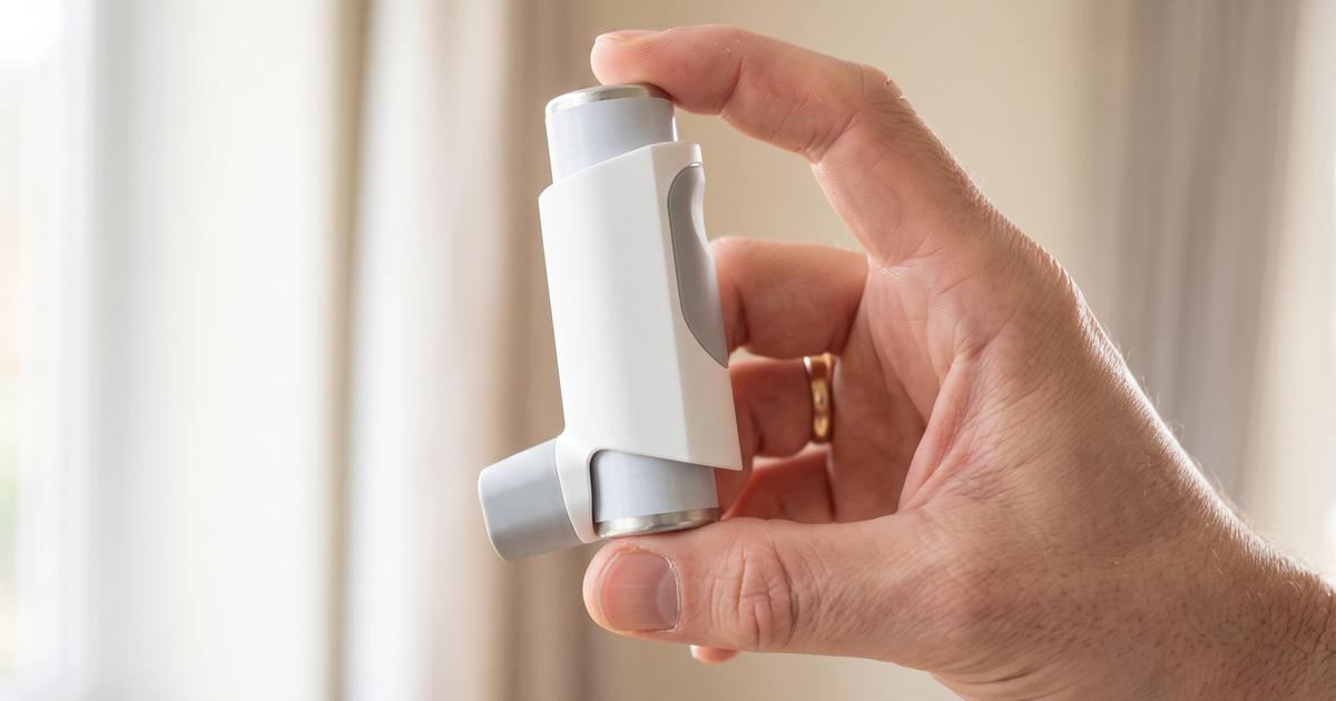 A hand holding an inhaler in soft natural light.