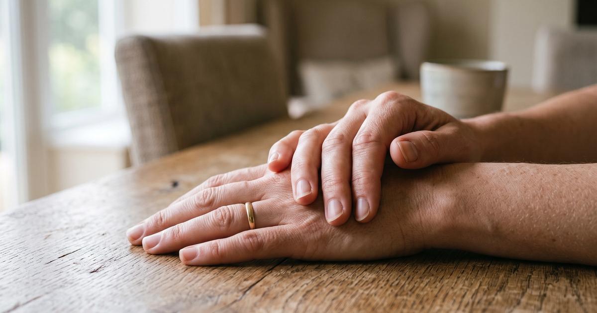 A close up of hands resting on a table in soft natural light.