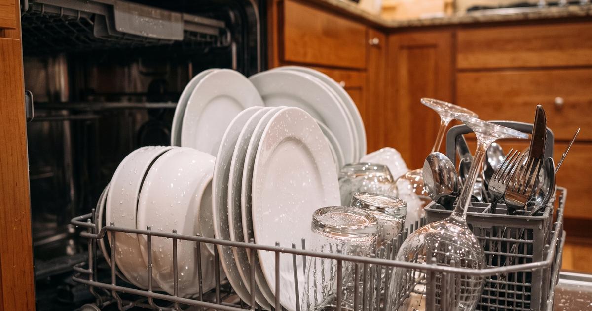 Plates and glasses loaded inside an open dishwasher rack.