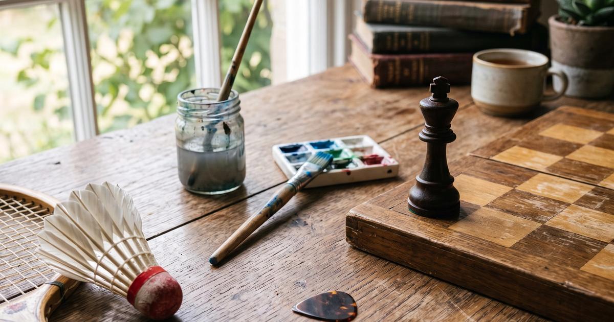 A variety of hobby items including a chess piece and paintbrush on a wooden table.