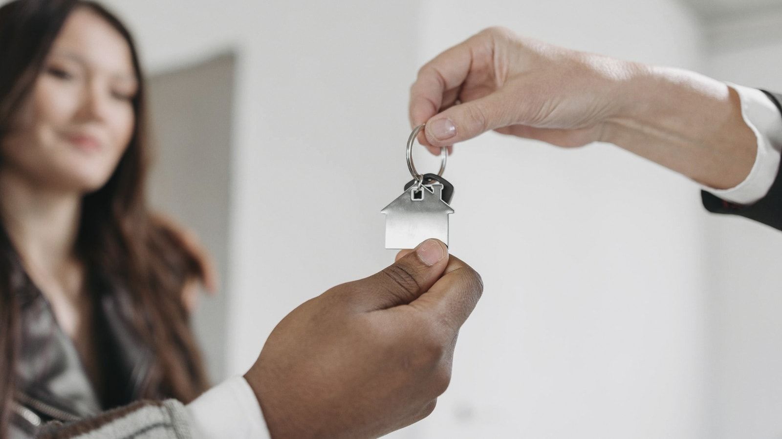 Close-up of a real estate agent handing over a house key to a client inside a new home.