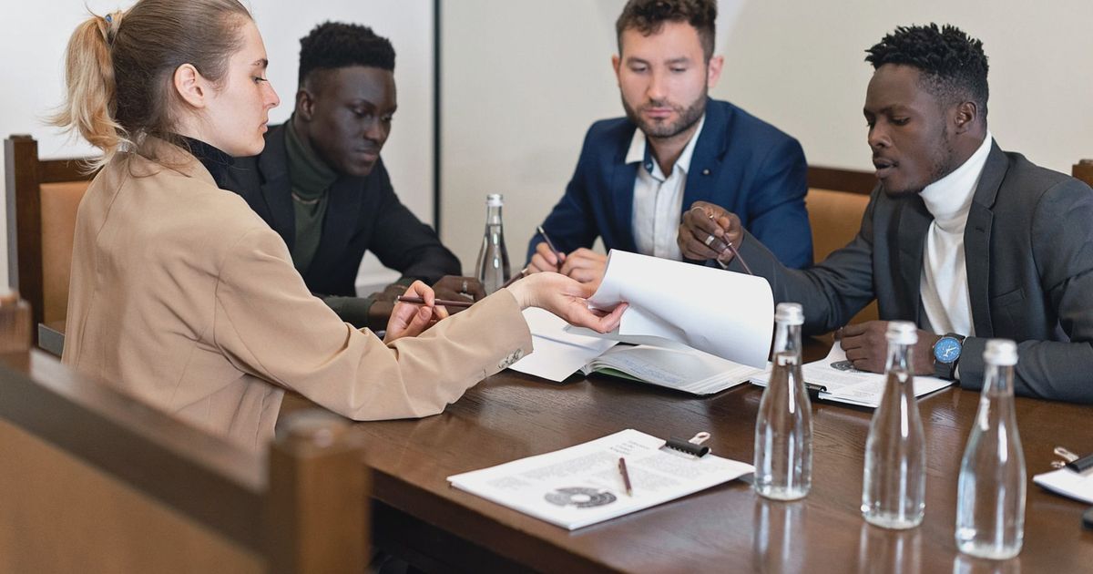 Business team in office meeting discussing contracts with diverse representation.