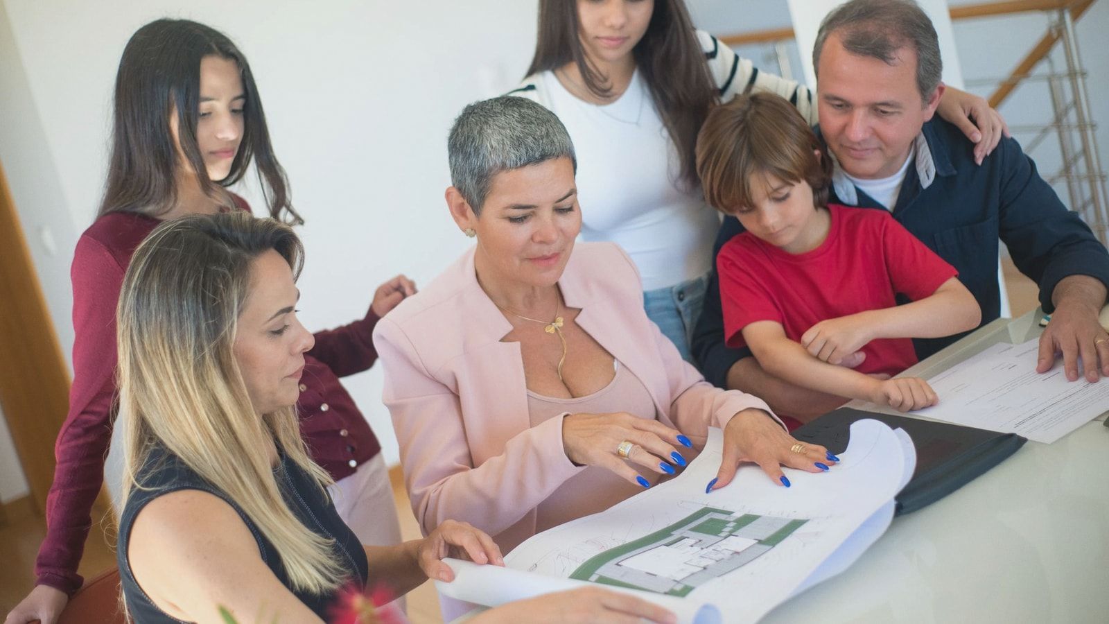 A family discusses property plans with a realtor indoors, focused on purchasing a new home.