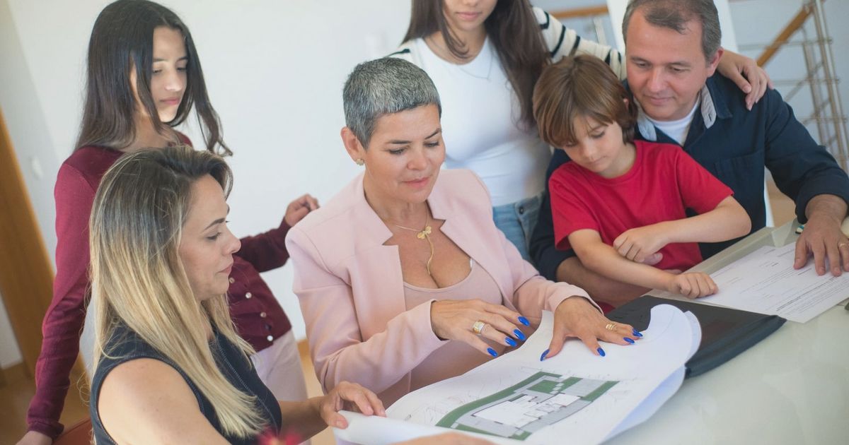 A family discusses property plans with a realtor indoors, focused on purchasing a new home.