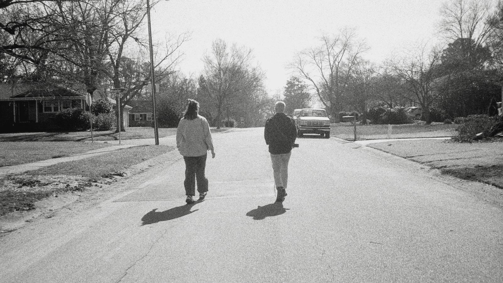 Two people walk down a suburban street