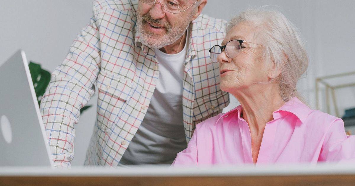 A senior couple enjoying time together while using a laptop, showcasing love and technology.