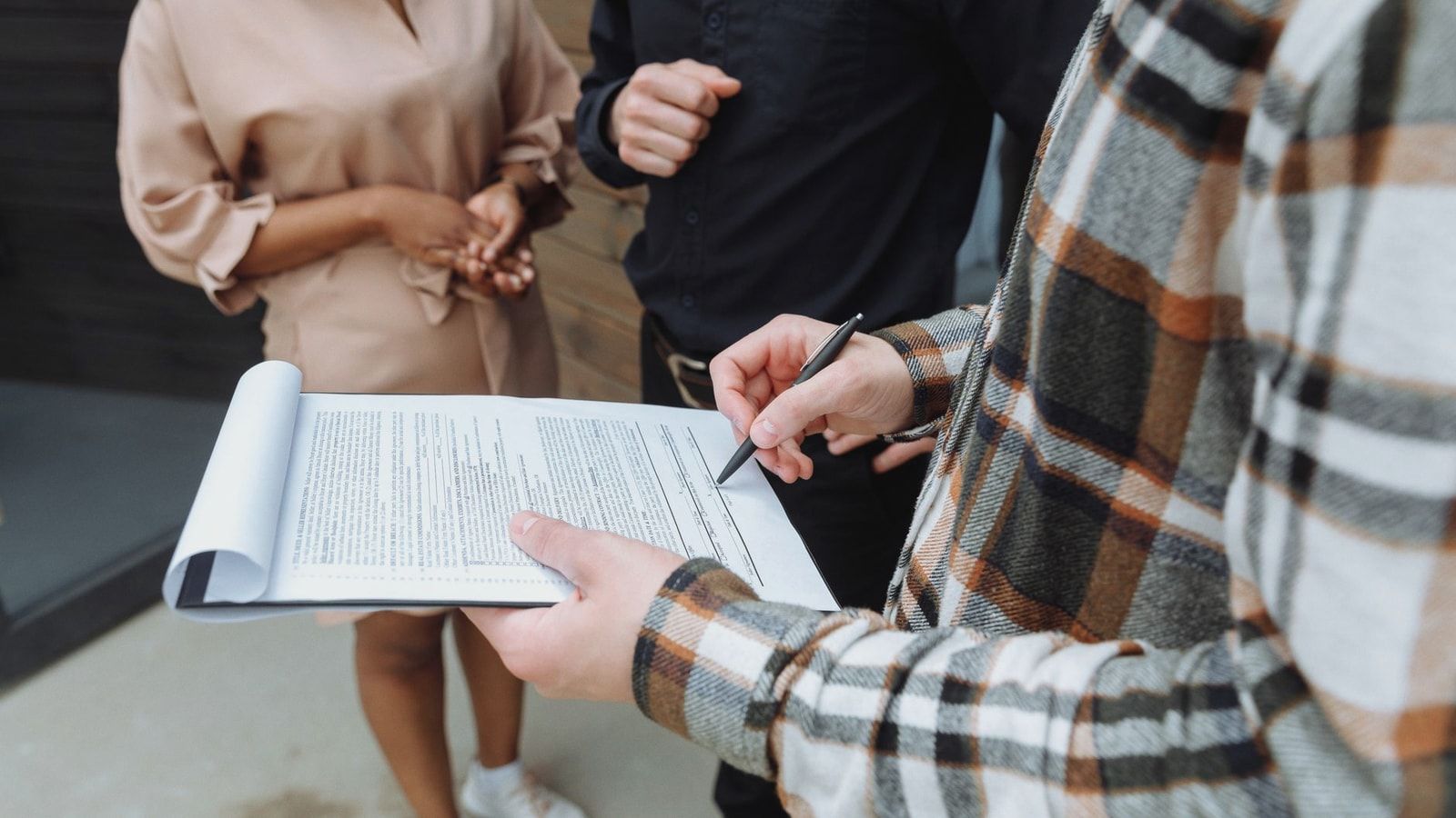 Three adults in an office setting discussing and signing a document.