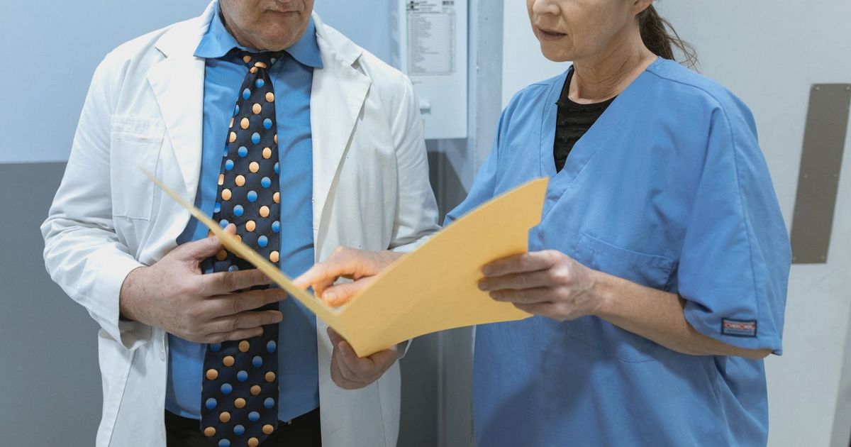 Doctor and nurse examining patient records in a clinical setting.