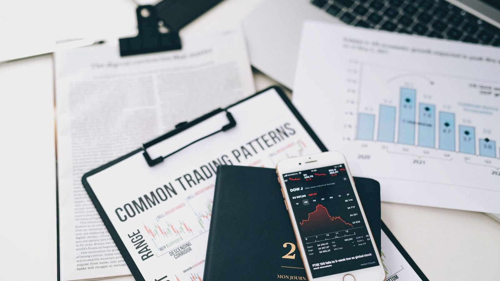 Overhead view of financial graphs and smartphone displaying stock market trends on a desk.