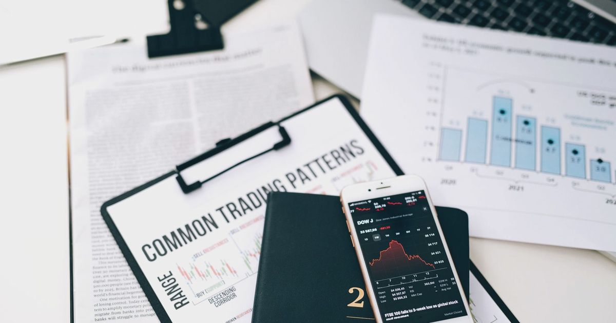 Overhead view of financial graphs and smartphone displaying stock market trends on a desk.