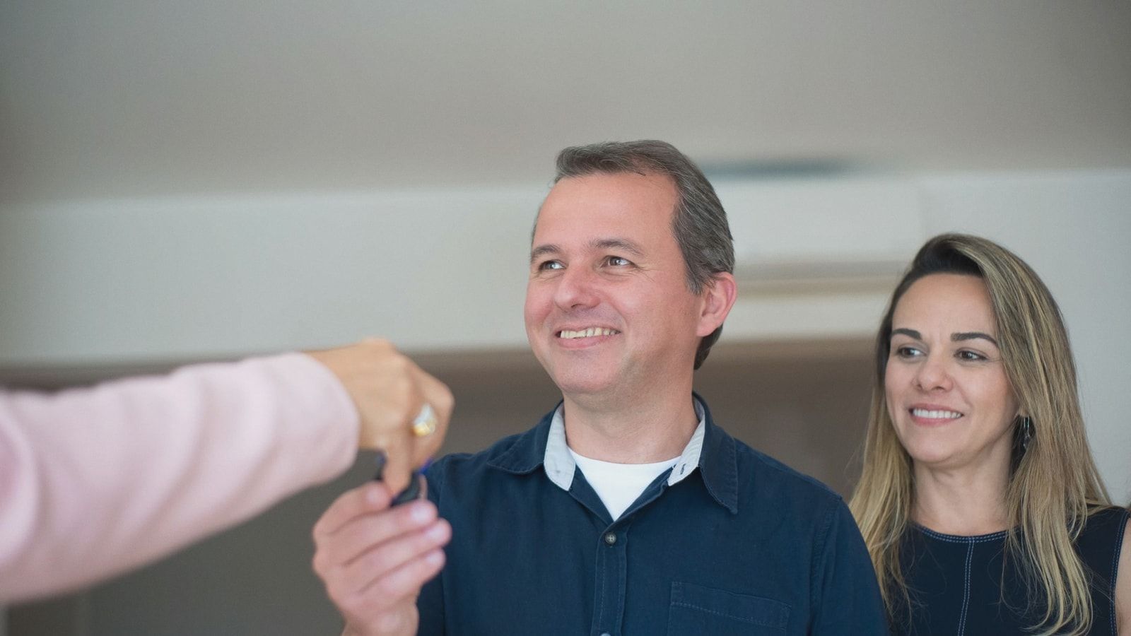 Smiling couple receiving keys, celebrating new home purchase indoors.