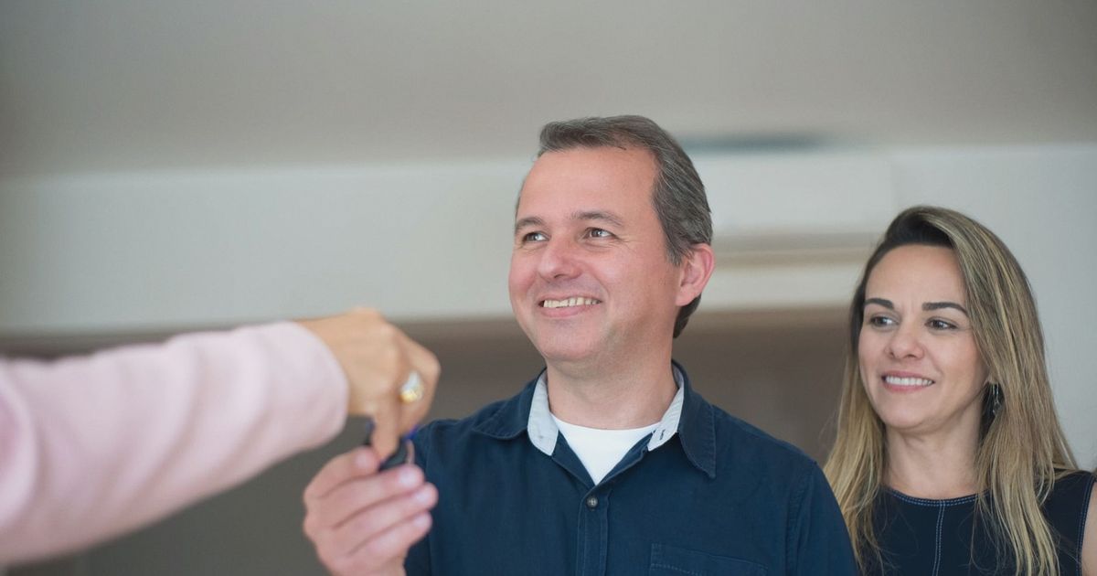 Smiling couple receiving keys, celebrating new home purchase indoors.