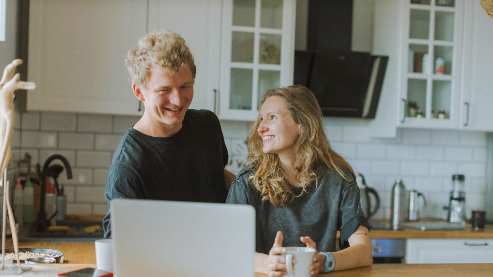 A cheerful couple shares a coffee and laughter in their modern kitchen, creating a cozy atmosphere.