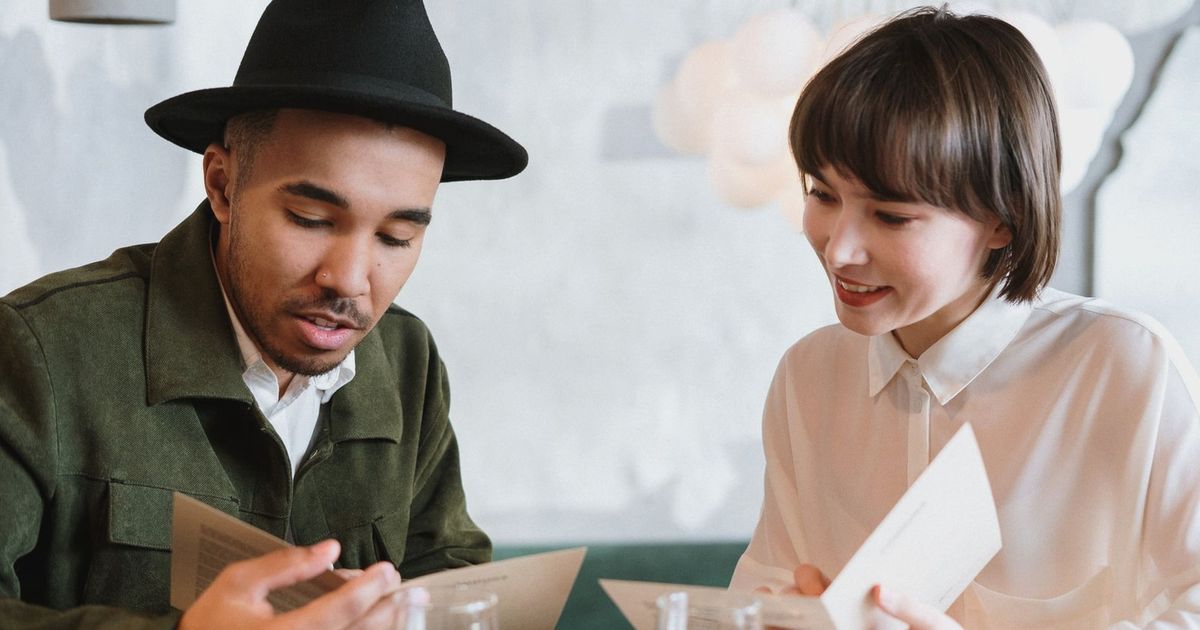 A couple sitting at a café table browsing menus together.