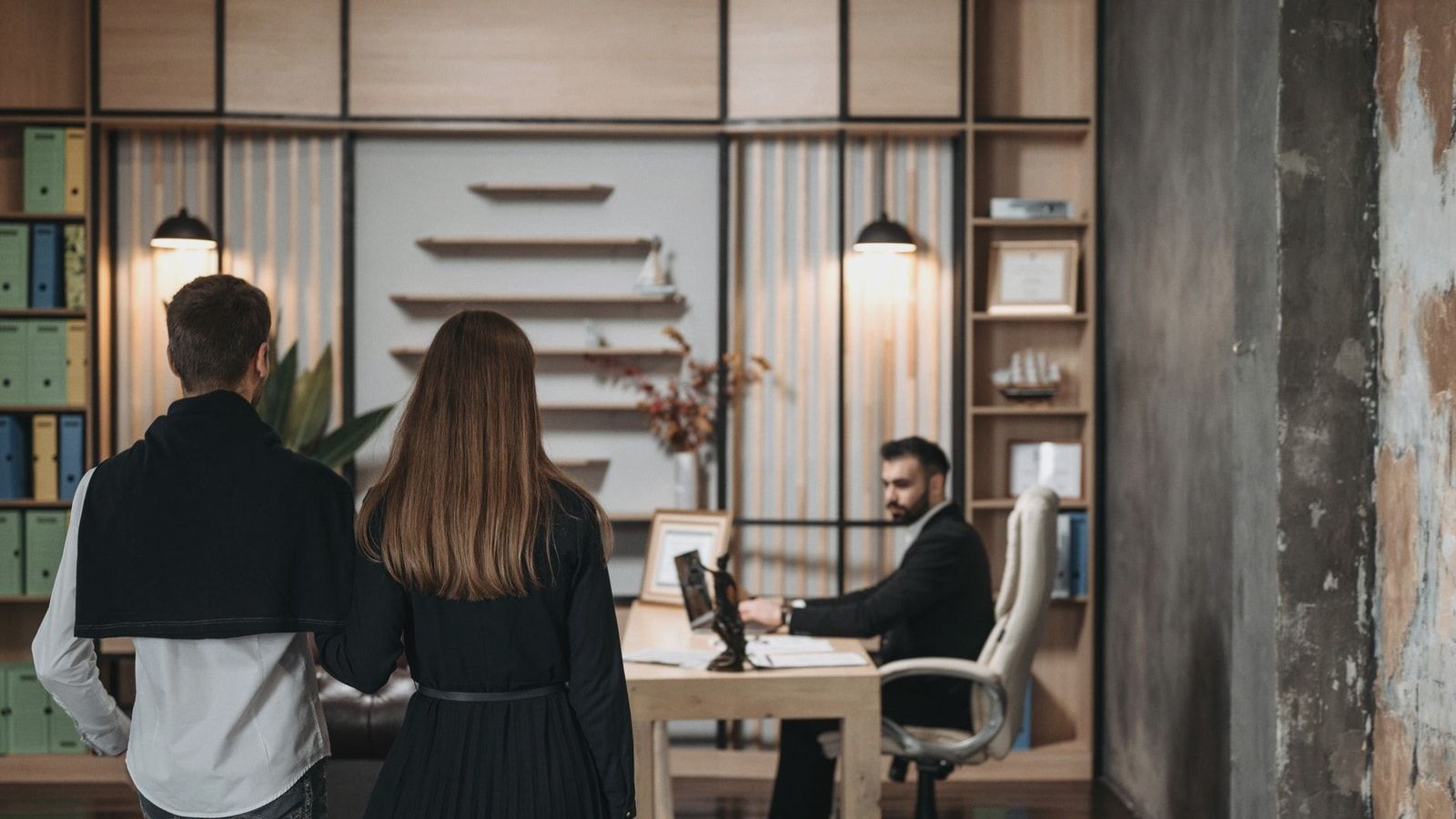 A couple approaches a lawyer in a contemporary office setting for a professional consultation.
