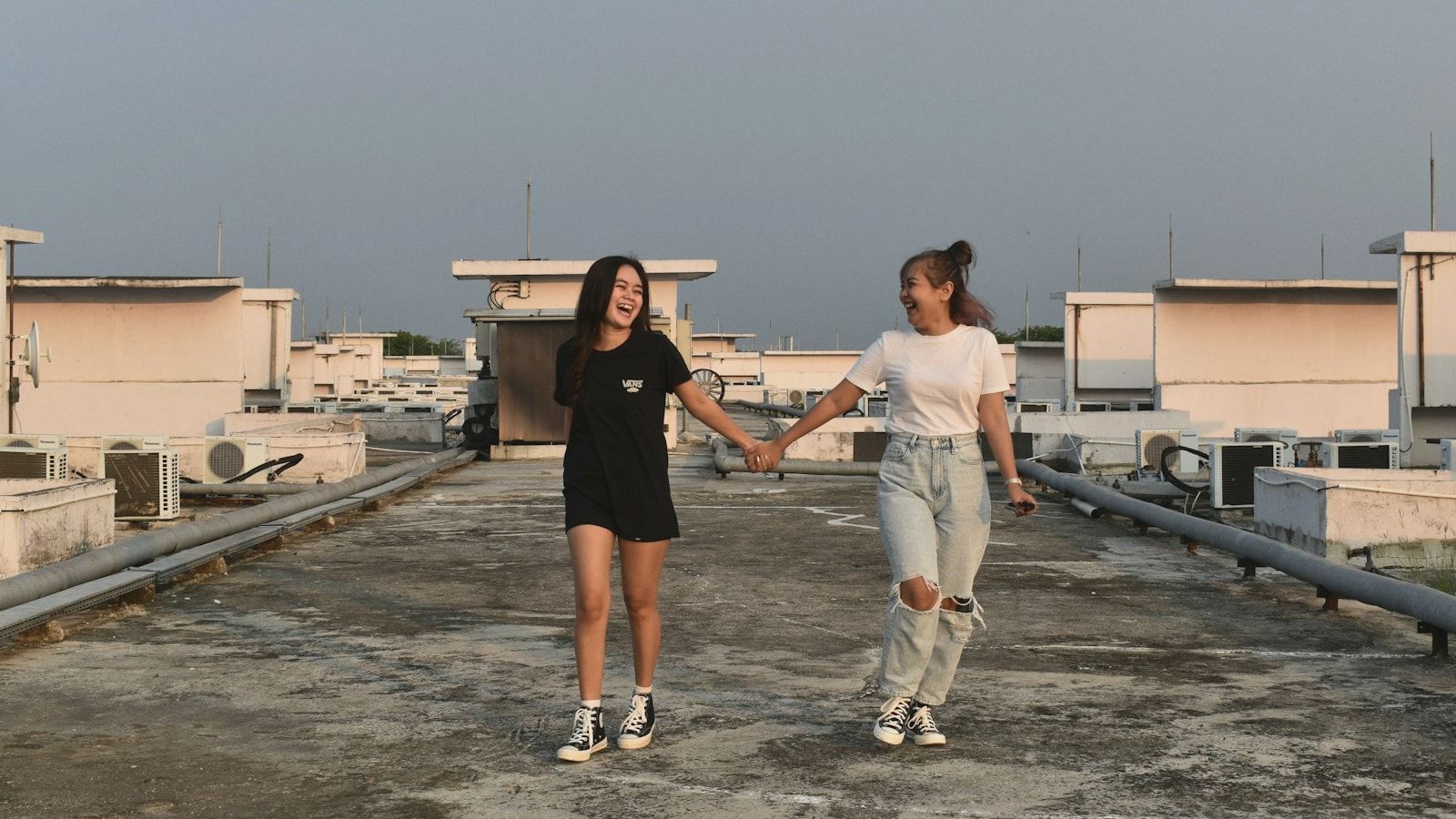 two women holding hands on a roof of a building
