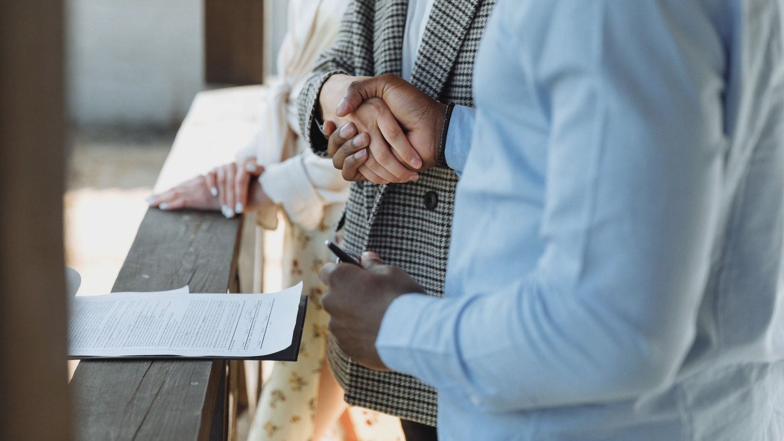 A close-up of hands shaking over a signed property agreement, symbolizing a successful real estate deal.
