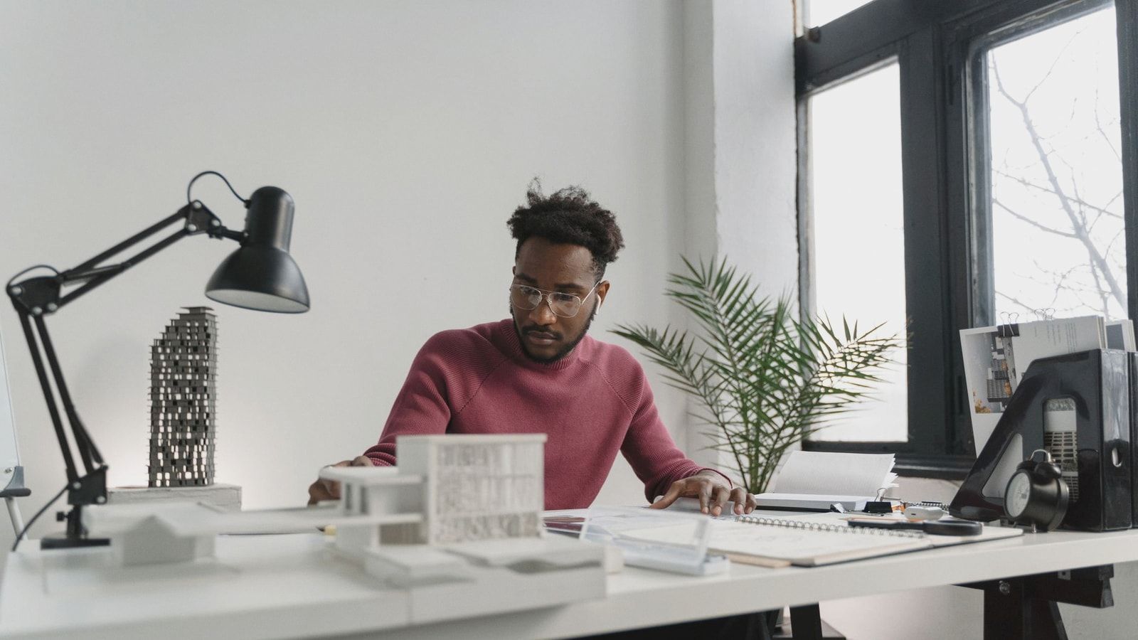 Professional architect working on building plans in a modern office setting.