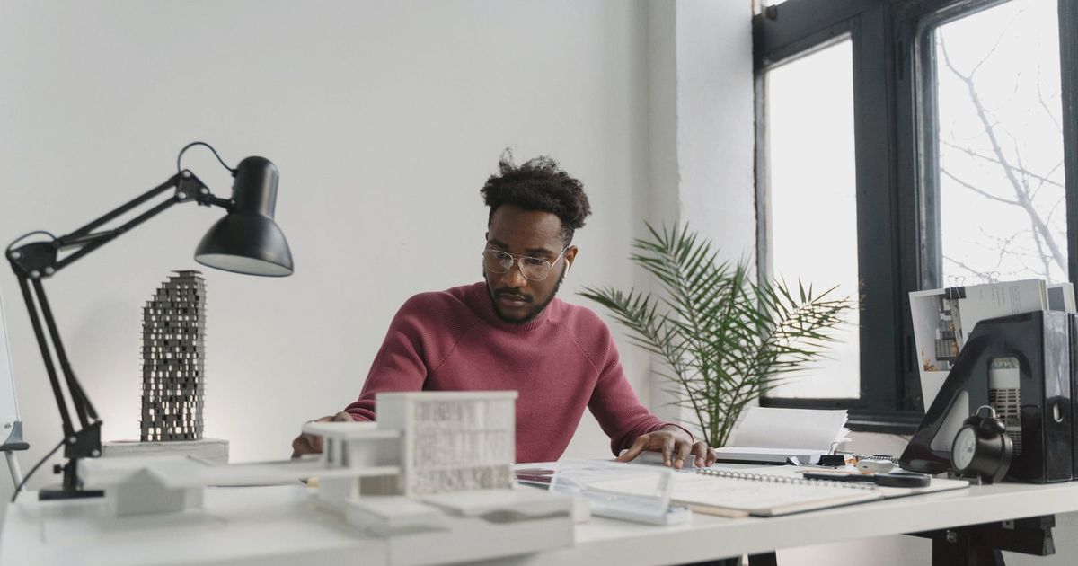 Professional architect working on building plans in a modern office setting.