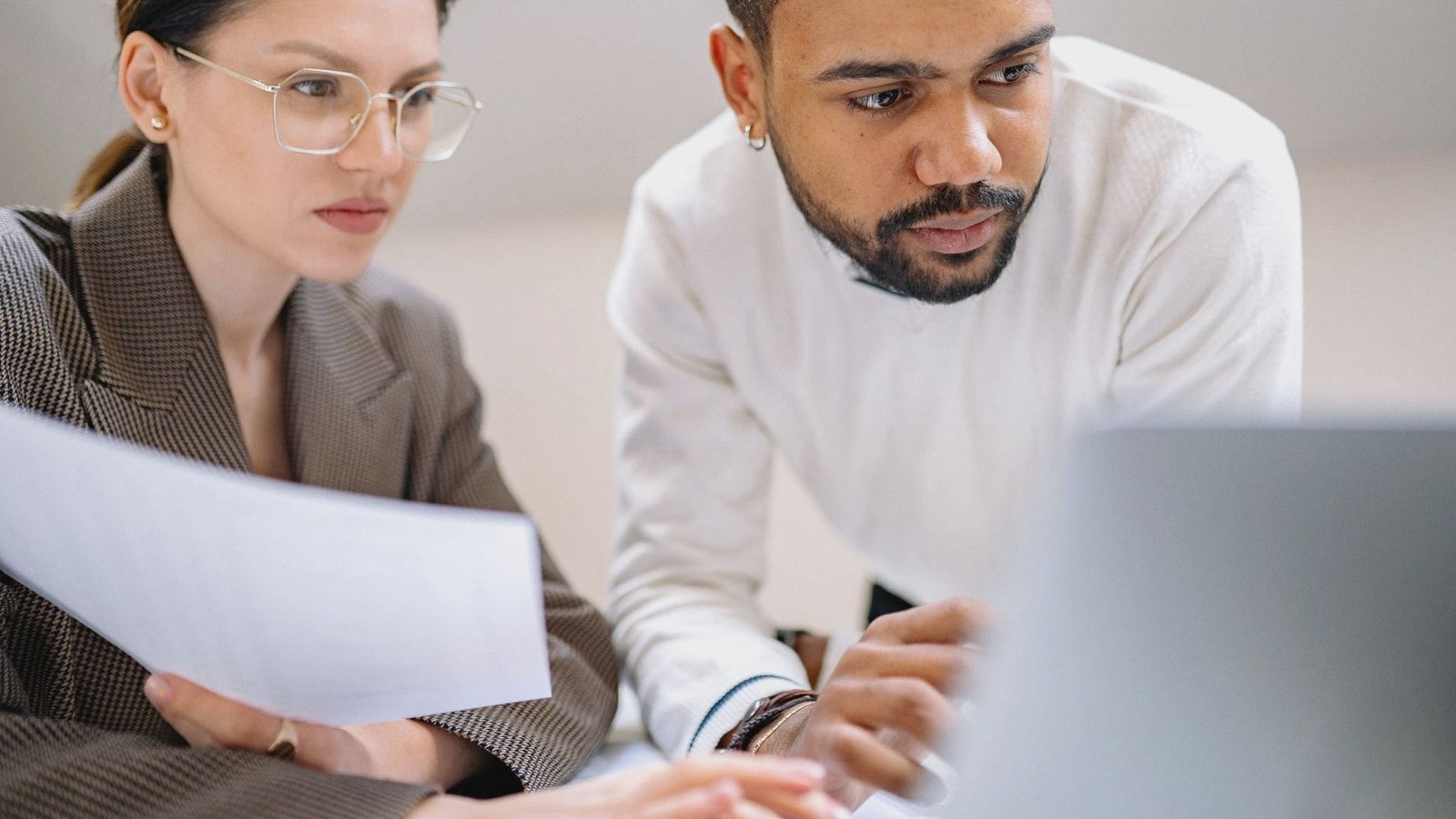 Two colleagues engaged in teamwork, analyzing documents in a modern office environment.