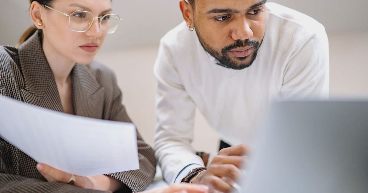 Two colleagues engaged in teamwork, analyzing documents in a modern office environment.