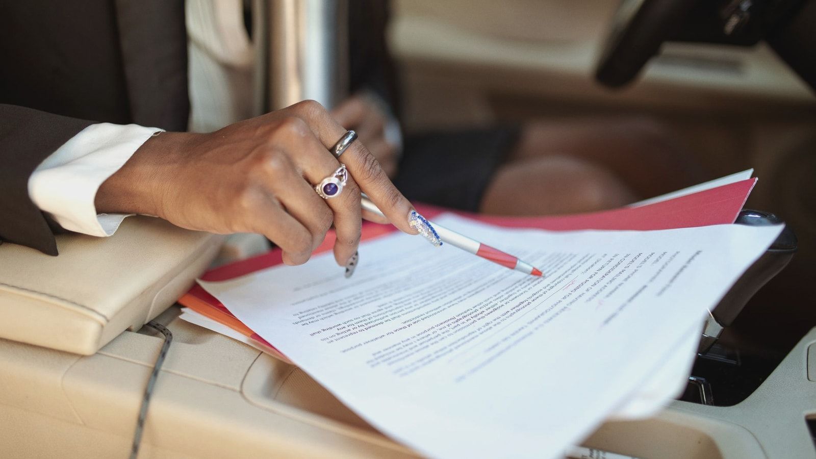 A professional reviewing documents in a car interior, focusing on hand and paperwork.