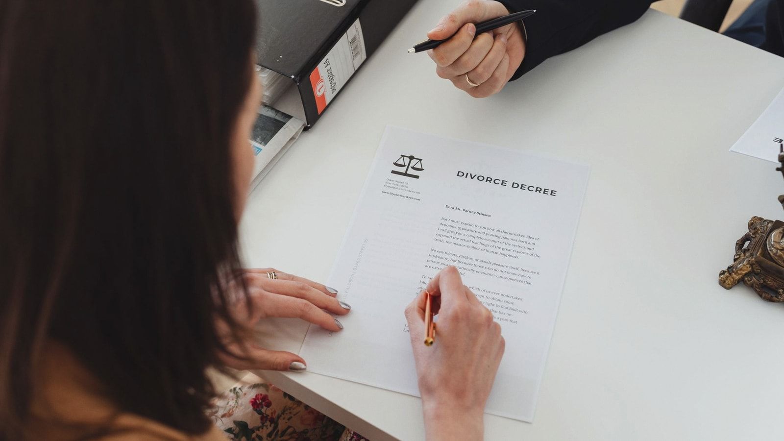 A person signing a divorce decree document with focus on hands and paper.