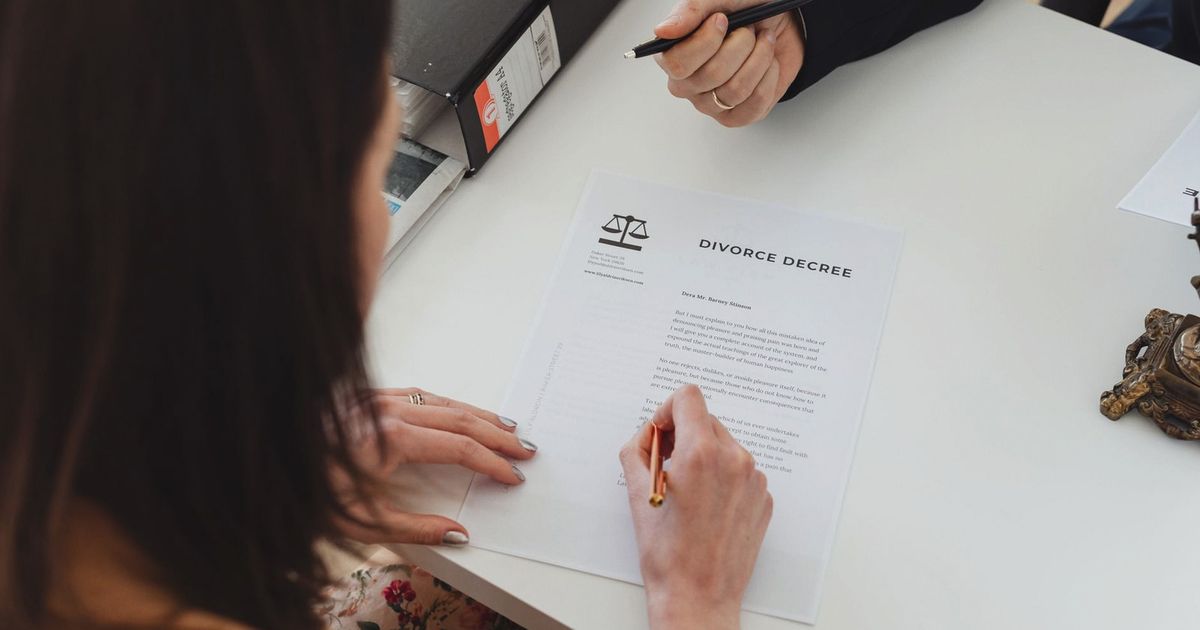 A person signing a divorce decree document with focus on hands and paper.
