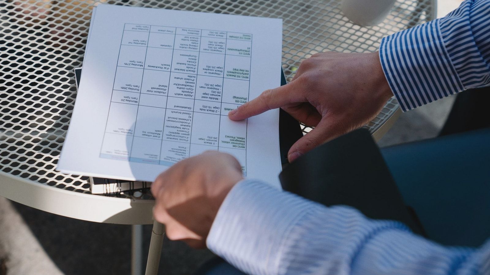 Professional reviewing a document outdoors at a table during a business meeting.