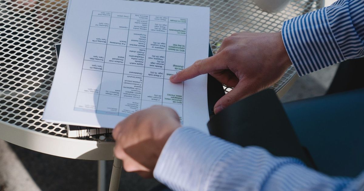 Professional reviewing a document outdoors at a table during a business meeting.