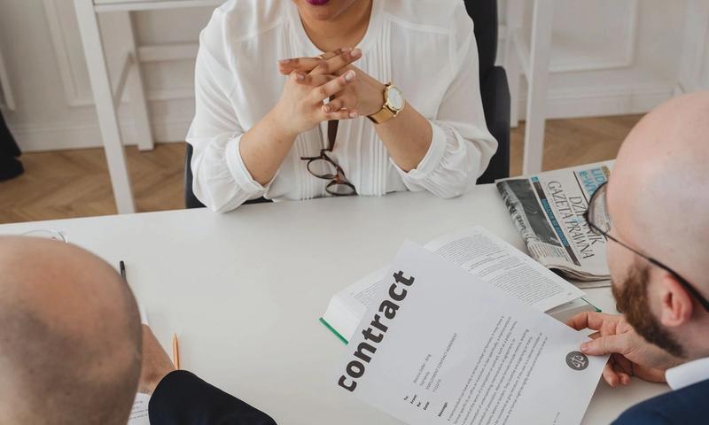 Business professionals discussing a contract in a modern office setting.