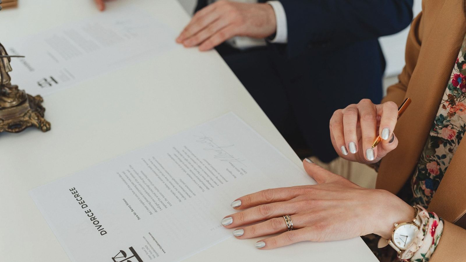 A detailed view of hands signing a divorce decree document at an indoor office meeting.