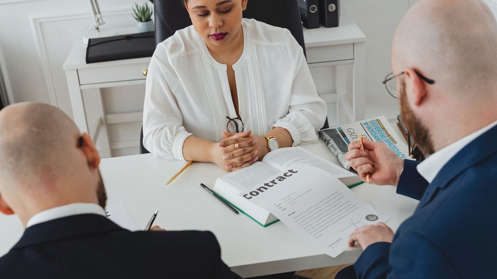 Professionals discuss a contract in a modern office setting, focusing on agreement details.