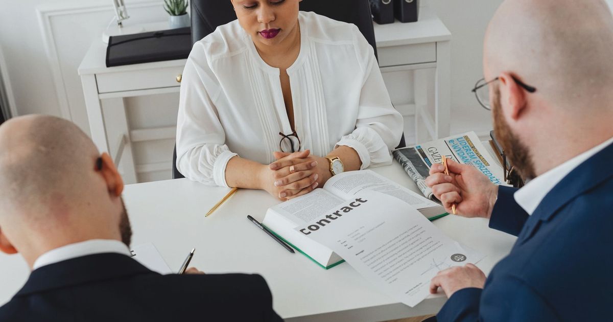 Professionals discuss a contract in a modern office setting, focusing on agreement details.