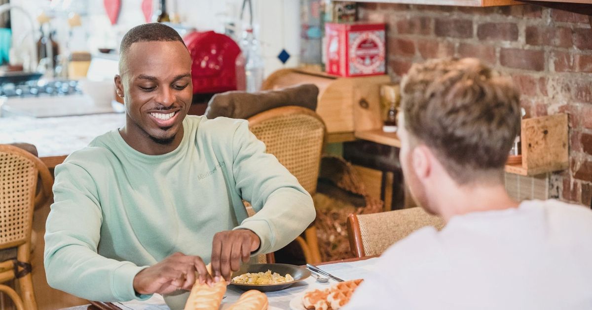Cheerful couple sharing a meal in the kitchen, embracing a cozy morning ambiance.