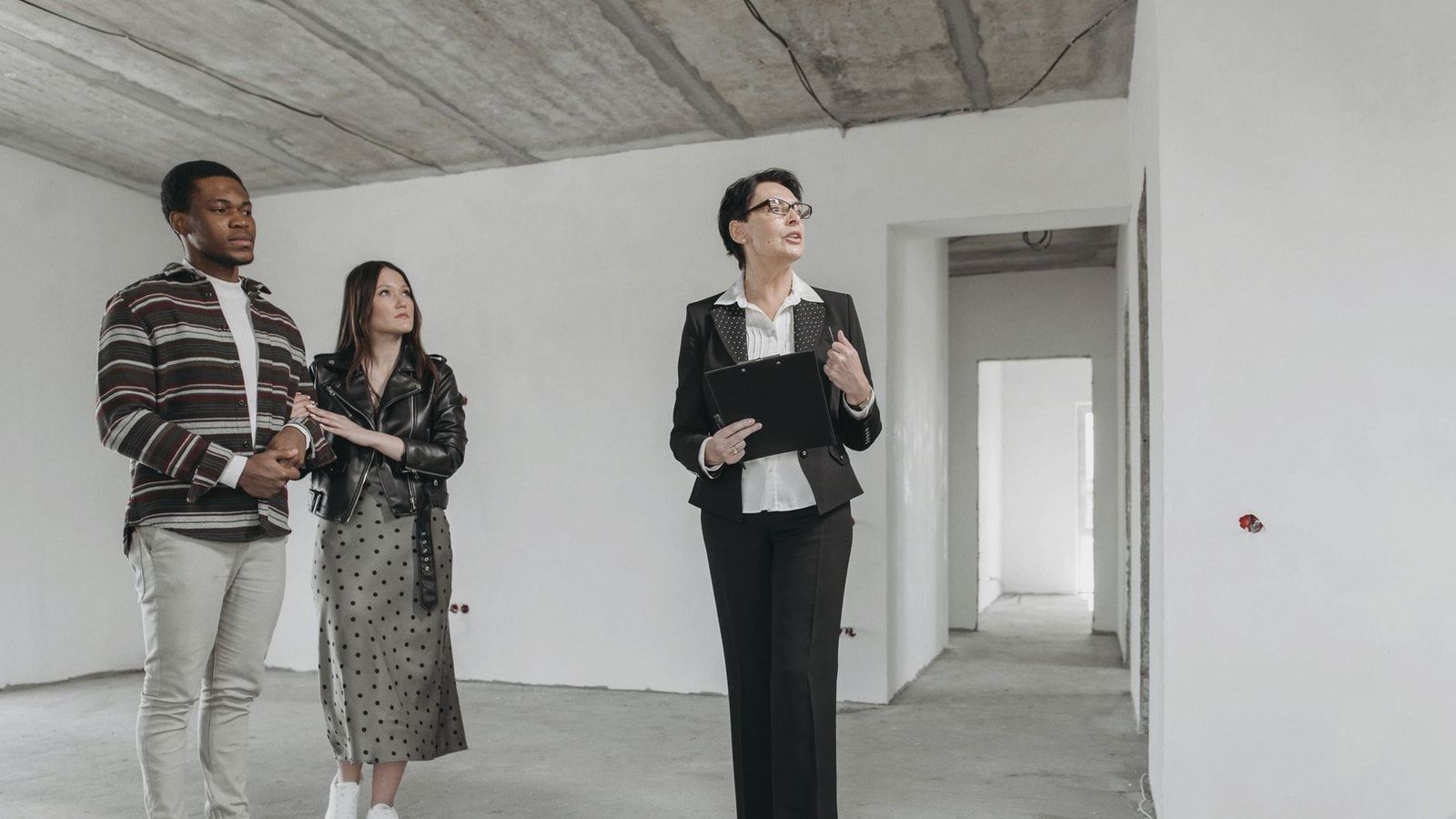 A real estate agent shows an unfinished apartment to prospective buyers.