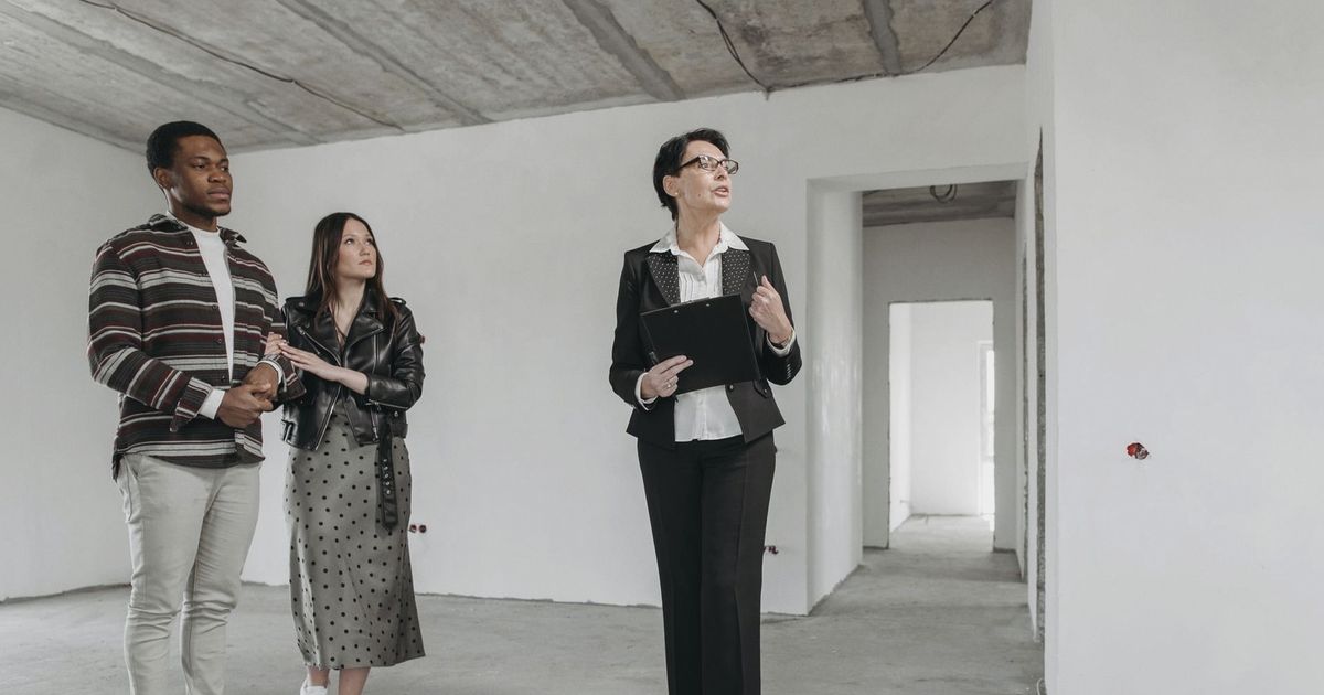 A real estate agent shows an unfinished apartment to prospective buyers.