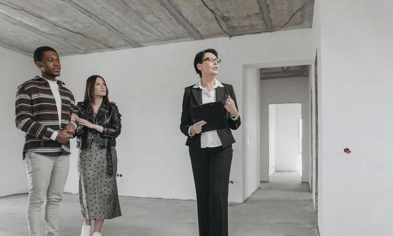 A real estate agent shows an unfinished apartment to prospective buyers.