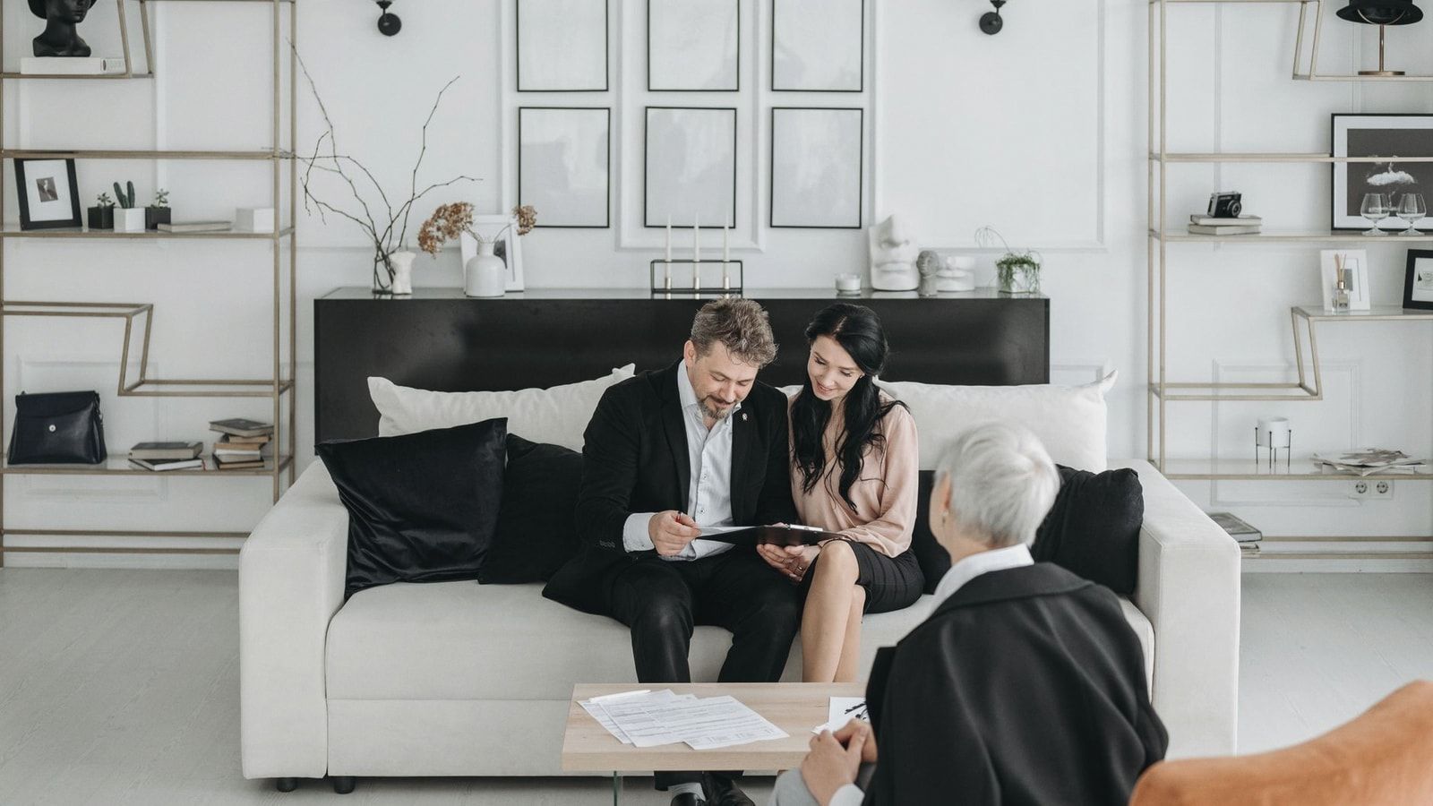 Couple consulting with a social worker in a modern living room setting, discussing documents.