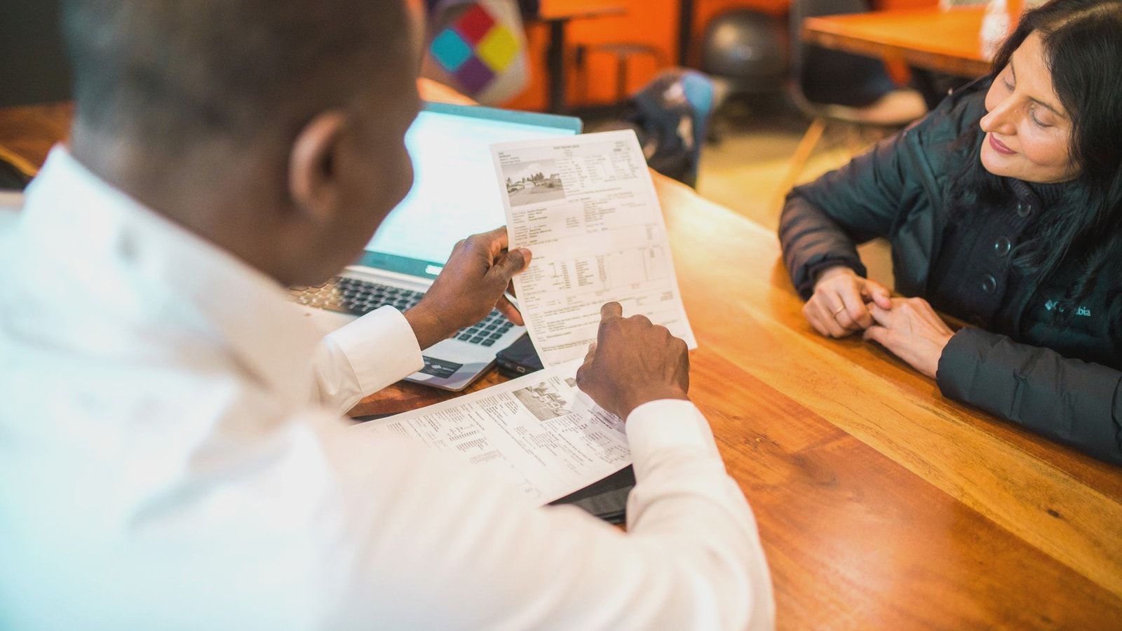 Two adults discussing documents in a business setting indoors.