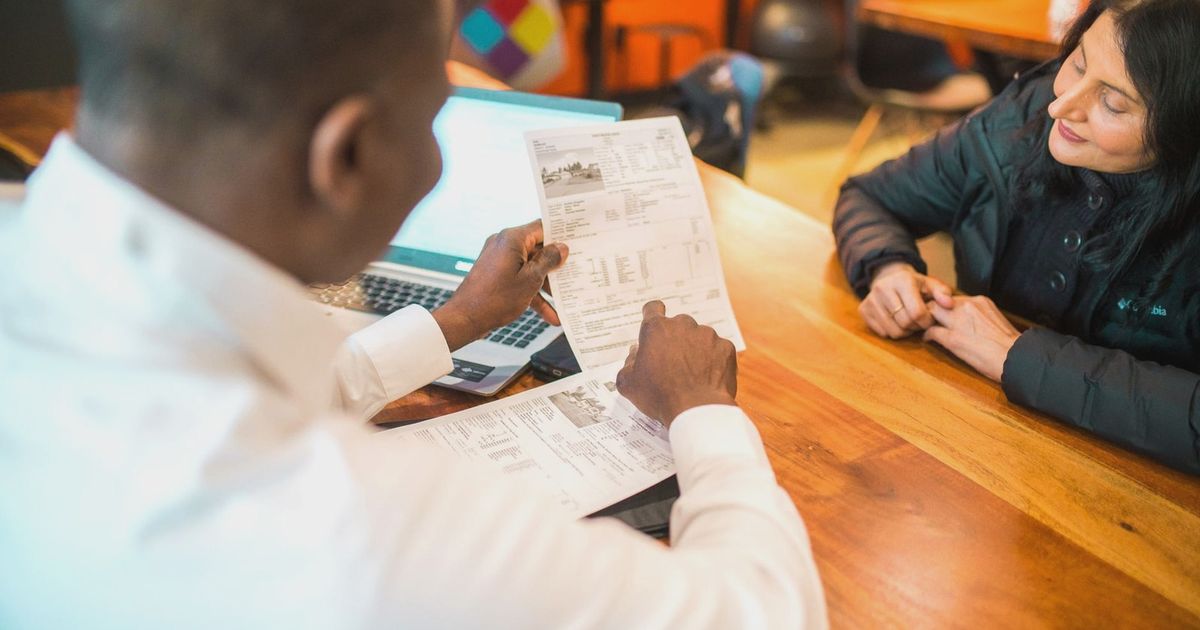 Two adults discussing documents in a business setting indoors.