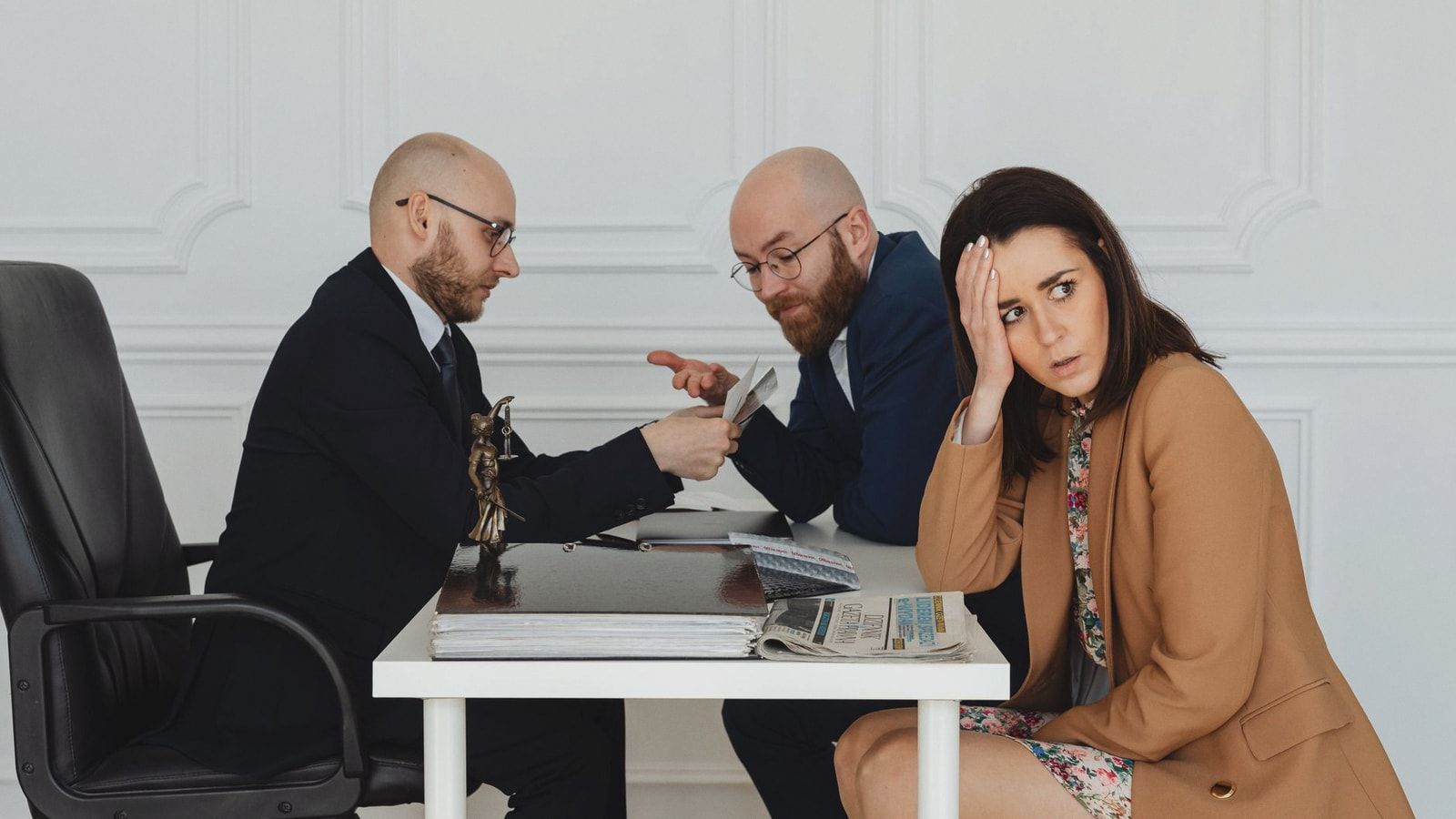 Two lawyers discuss documents with a worried client in a professional office setting.