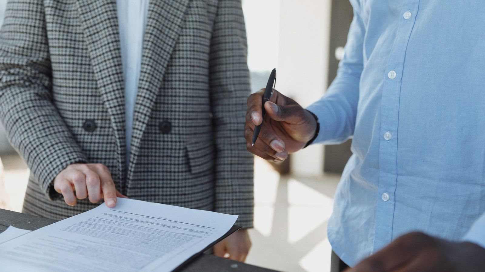 Two professionals reviewing business documents and discussing details in an office setting.