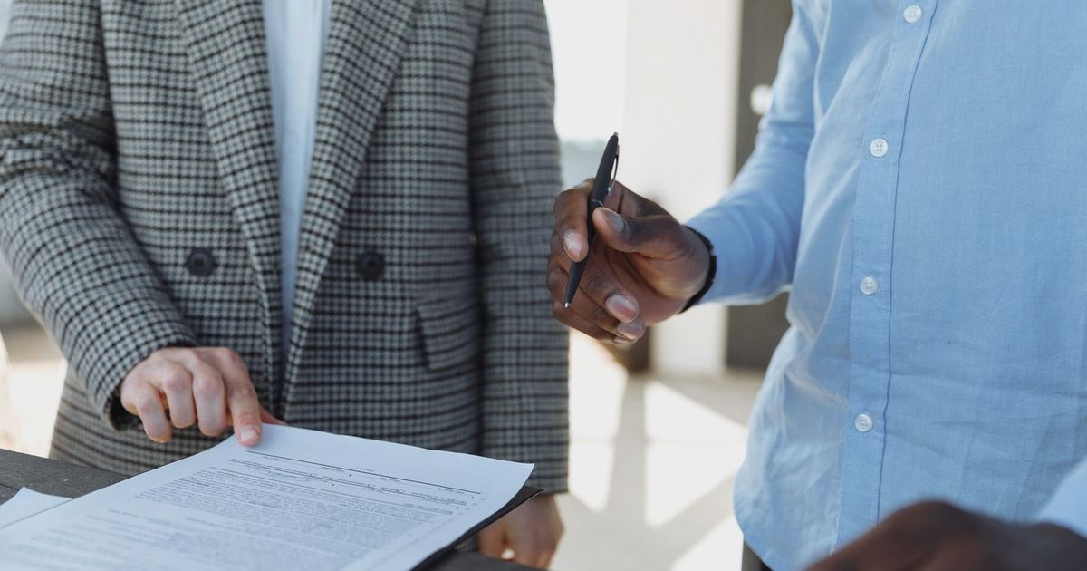 Two professionals reviewing business documents and discussing details in an office setting.
