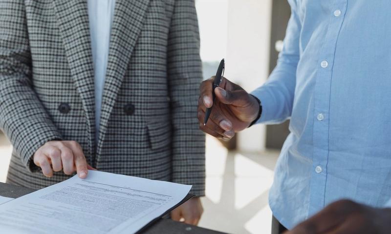 Two professionals reviewing business documents and discussing details in an office setting.