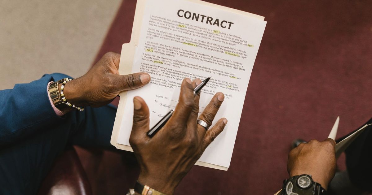Two businessmen reviewing and signing a contract document in an office setting.