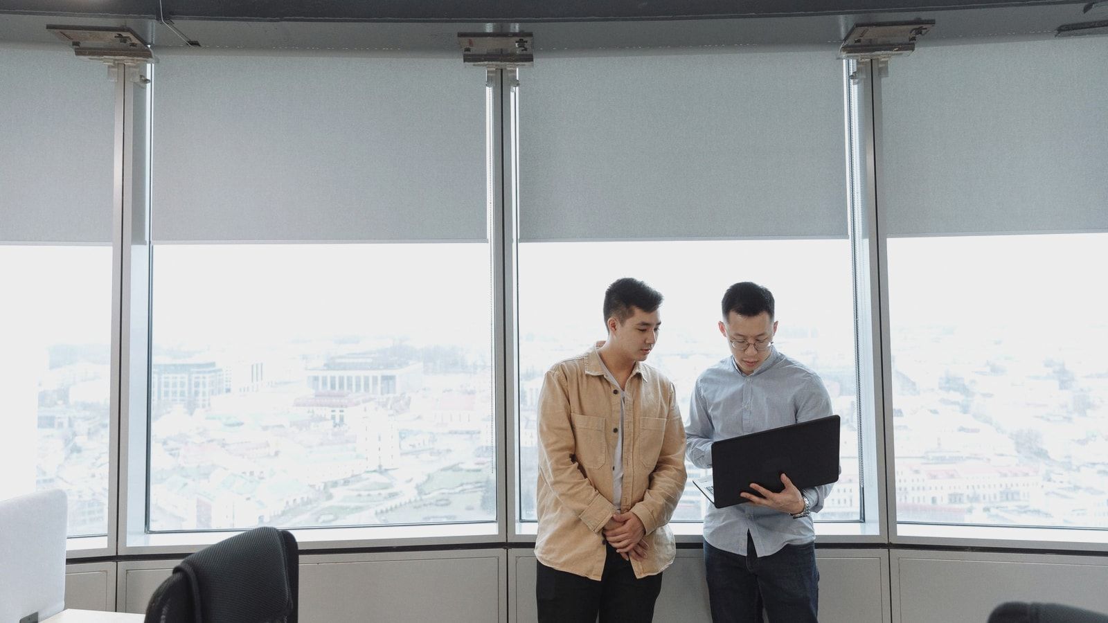 Two professionals discussing business strategy with a laptop in a modern office.