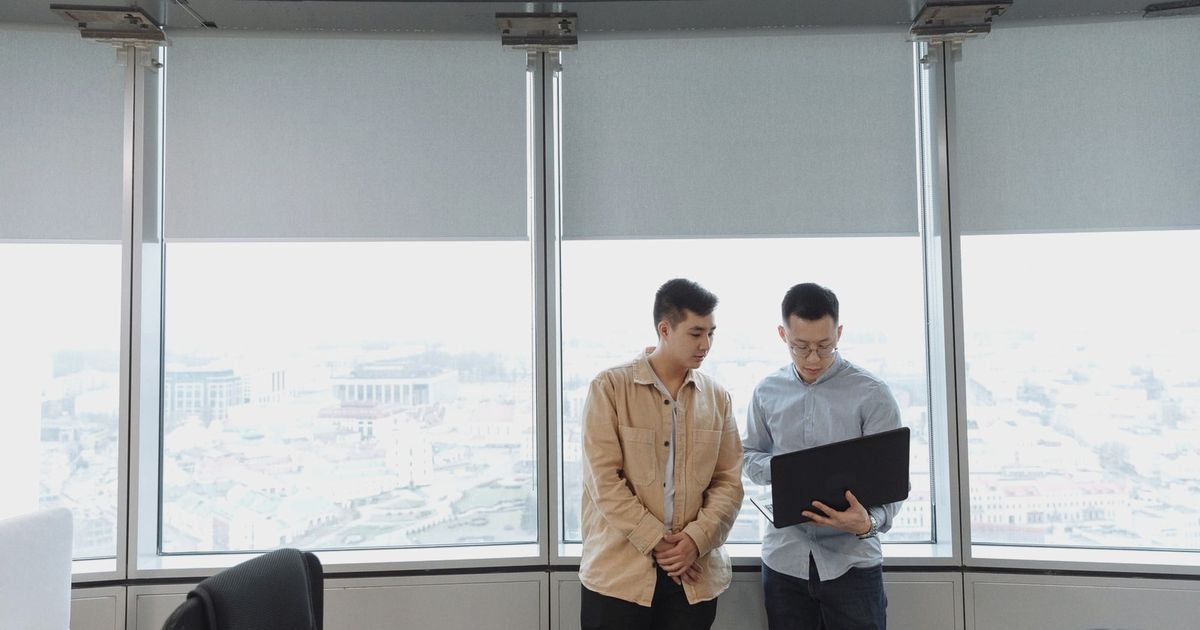 Two professionals discussing business strategy with a laptop in a modern office.
